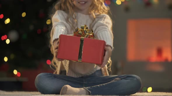 Little Girl Holding Out X-Mas Present to Camera, Holiday Decorations Sparkling