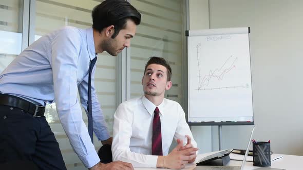 two young business man indoor office interior using personal computer discussing