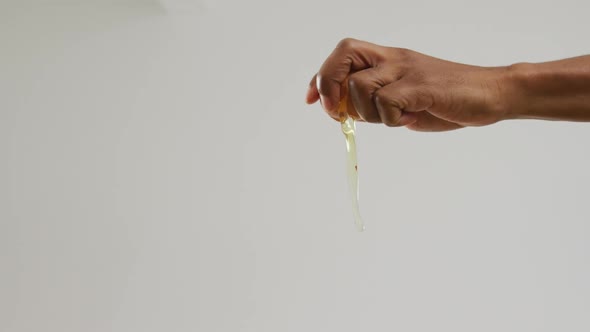 Video of hands of biracial man cracking egg on white background
