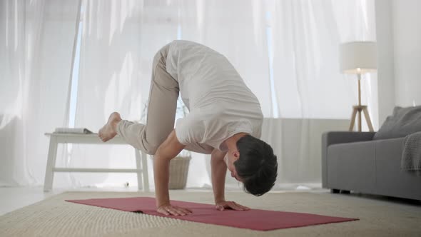 Young Man Practicing Yoga at Home: He Is Doing Bakasana. Simple Balance Yoga Asana Healthy Back Slow