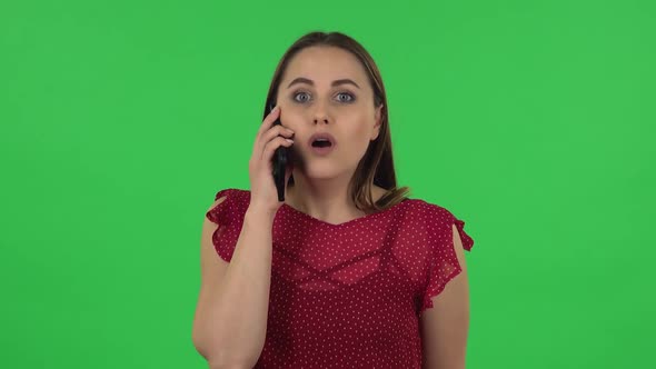 Portrait of Tender Girl in Red Dress Is Talking for Mobile and Shocked Then Rejoice. Green Screen