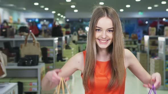 Happy Woman Holding Shopping Bags and Smiling at the Mall