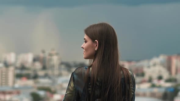 Woman with Long Loose Hair Poses for Camera Against City