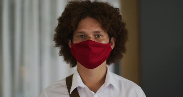 Portrait of mixed race man with curly hair wearing red face mask