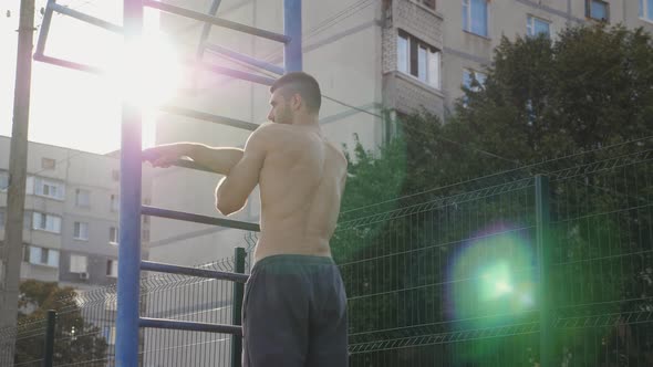 Muscular Athlete Doing Shoulder and Arm Stretching on Metal Railing Warming Up Before Intense