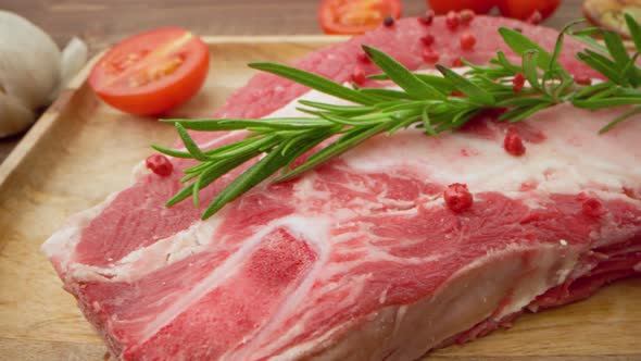 Fresh Raw Meat Steaks on Wooden Board with Spices Close Up
