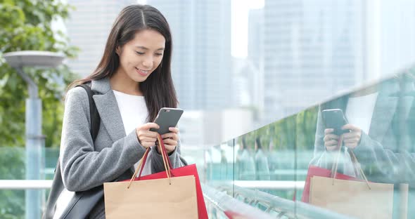 Woman holding shopping bag and use of mobile phone