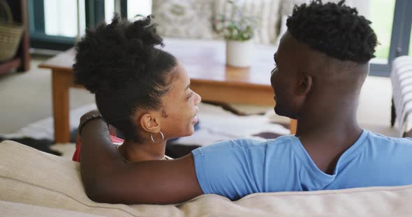 Video of happy african american couple sitting on sofa and embracing