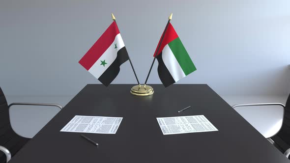 Flags of Syria and the UAE and Papers on the Table