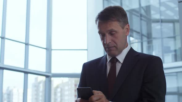 Mid-Aged Businessman Messaging on Smartphone
