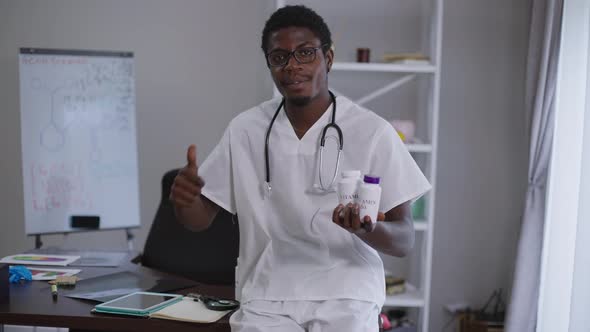 Confident Smiling African American Doctor in Eyeglasses Gesturing Thumb Up Looking at Camera