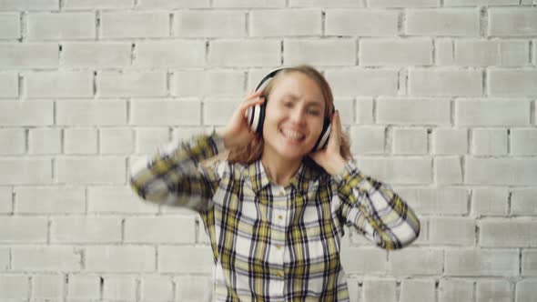 Portrait of Happy Girl in Stylish Clothing Dancing, Singing and Listening To Music in Wireless