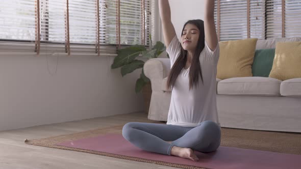 Morning yoga with an Asian woman, sitting in Easy position, Sukhasana posture