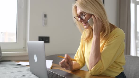 Portrait of a Charming Mature Midage Blonde Woman in Glasses Using a Smartphone