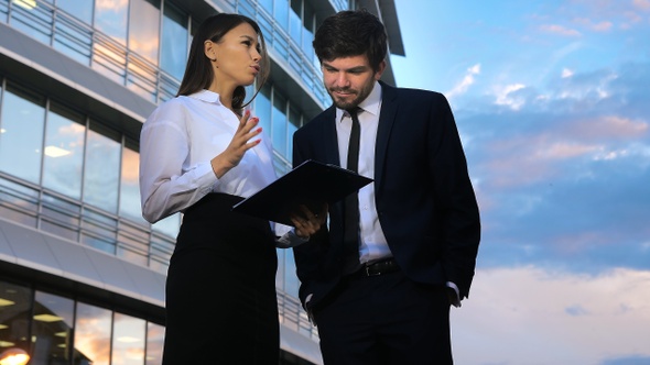 Elegant woman secretary showing documents to her boss giving