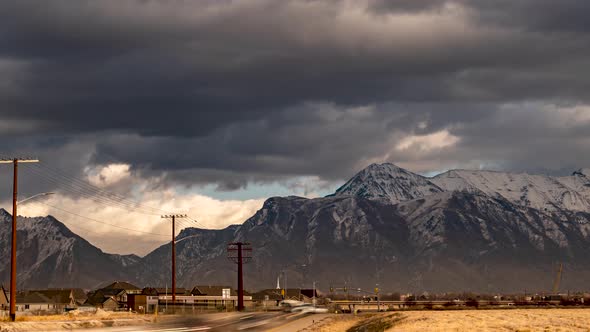 With a dramatic cloudscape overhead, traffic speeds along the highway in the valley below the snow m