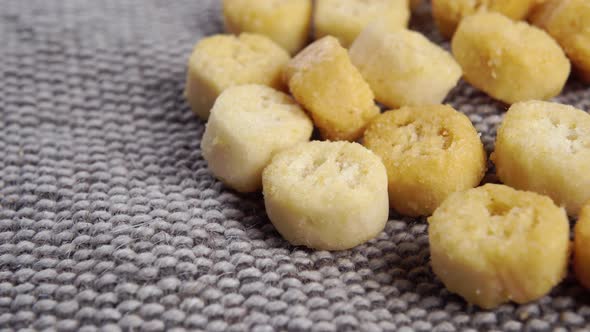 Round small croutons on a rough jute burlap close up. Crunchy salad ingredient. Macro