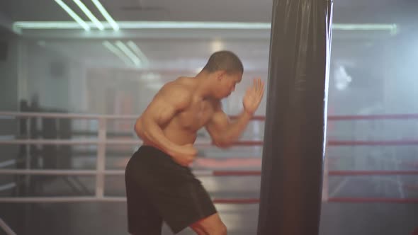 Kickboxing Athletic Man Fighter Trains His Punches Beats a Punching Bag Training Day in the Boxing