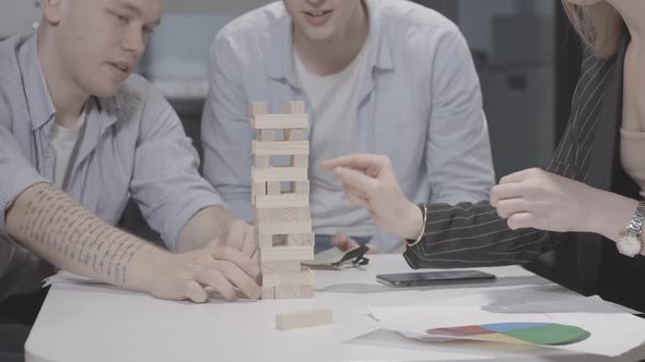 Portrait of Young Positive Bald Man Playing Jenga with Coworkers