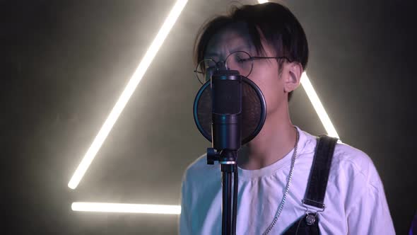 Young Modern Asian Man Singing Into a Microphone in a Recording Studio