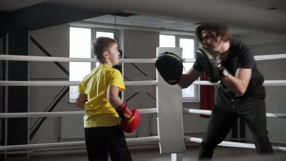 Little Boy Training Boxing with a Young Man Coach on the Ring