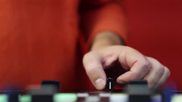 Disc jockey plays music with mixing controller device in close up footage