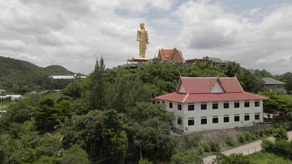 Wat Khao Noi Temple on Hilltop, Huge statue of Standing golden Buddha, Thailand. Aerial Upwards
