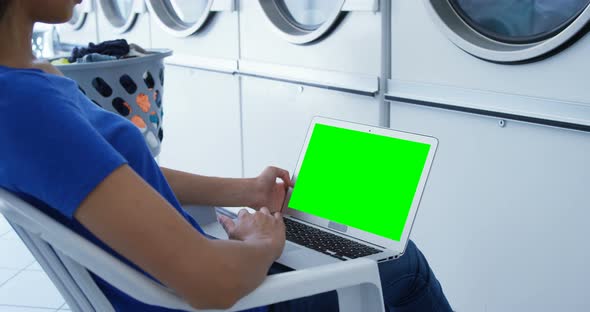 Woman using laptop at laundromat 4k