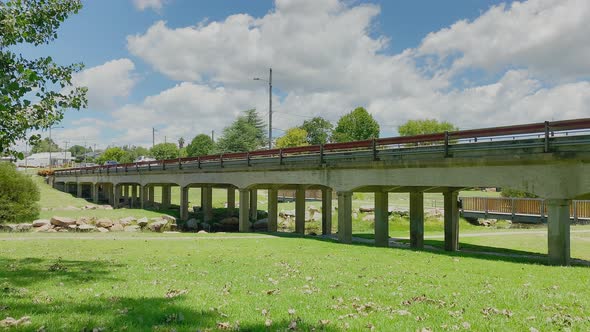 4K UHD Time-lapse of car traffic crossing bridge on road on a sunny day with white clouds above in d