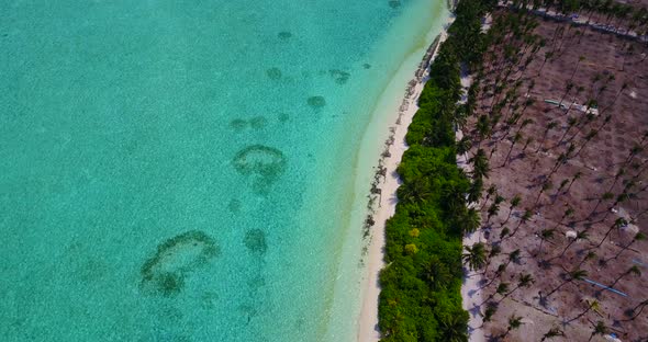 Wide angle fly over island view of a white sandy paradise beach and blue sea background in vibrant 4