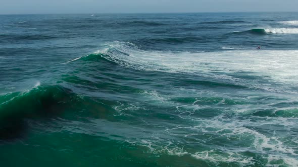 Azure Sea with Waves and Surfer Under Clear Sky Aerial View