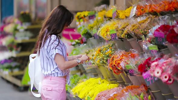 Beautiful Young Woman with Long Hair Selecting Fresh Flowers at European Market