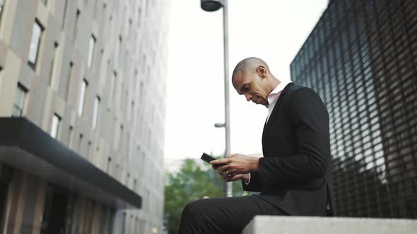 Concentrated African businessman typing on mobile
