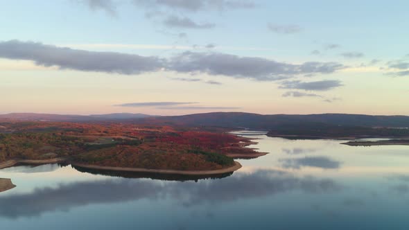 Drone aerial view of a lake reservoir of a dam with perfect reflection on the water of the sunset in