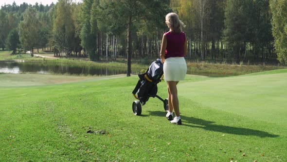 Summer Day Woman Playing Golf Walking with a Cart in Her Hands Golf Clubs in Her Bag View of Golf