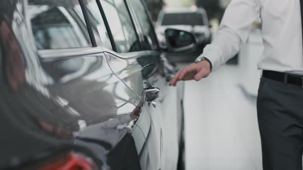 Unrecognizable Salesman Opening Car Door in Dealership