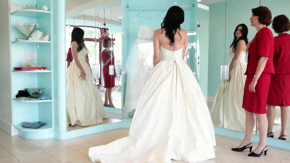 Daughter trying on wedding dress with mother