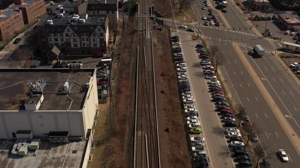 A top down shot of train tracks on a sunny day. On the left are warehouses and apartment buildings a