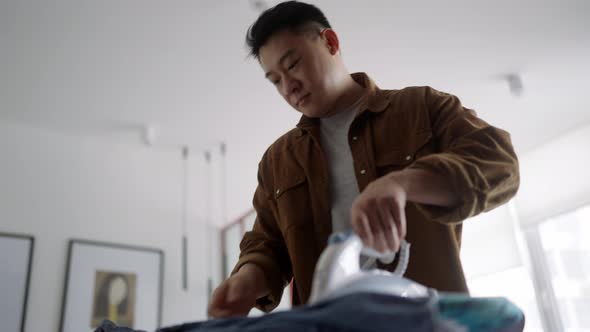 Handsome Asian man ironing clothes