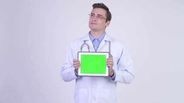 Young Happy Handsome Man Doctor Thinking While Showing Digital Tablet