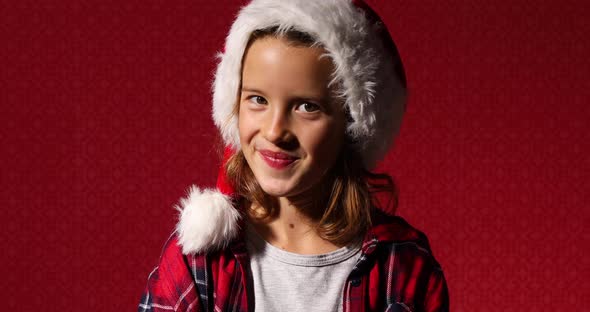 Portrait of Christmas Little Girl in Santa Hat Trying to Be Serious but Smile Laugh