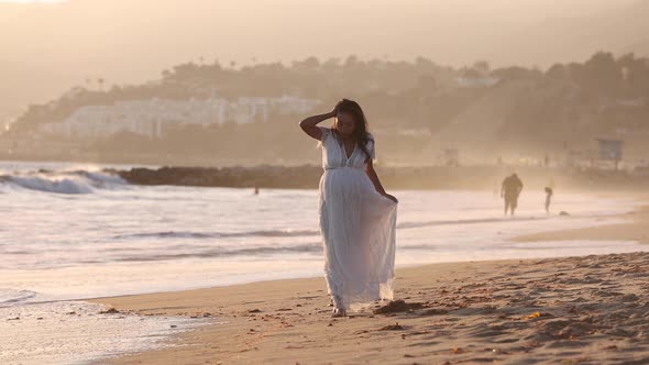 Pregnant Asian woman enjoying walk on the beach