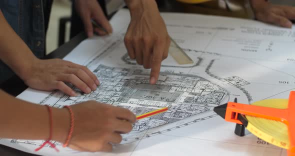 Architects Discussing At The Table With Blueprint