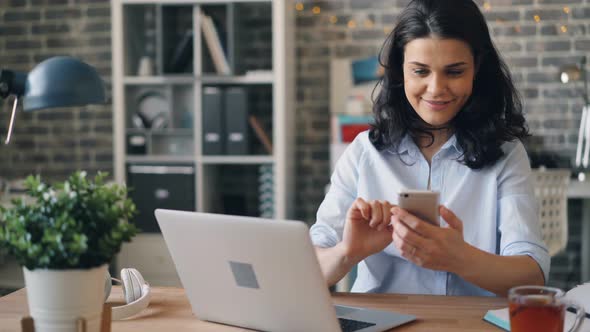 Beautiful Young Woman Texting with Smartphone Touching Gadget Screen at Work