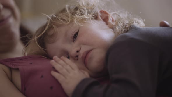 a disgruntled child lies on his mother's chest