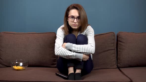 A Young Woman in Glasses Reads Nervously Watching Television, The Girl Climbed Onto the Sofa 