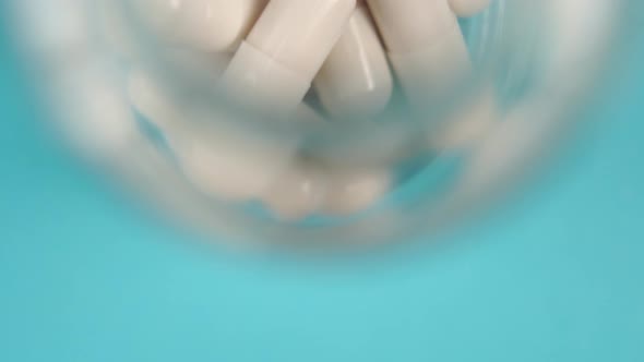 White medicine capsules close-up in a glass pharmaceutical bottle 