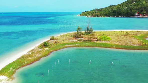 Natural harbor bordered by sandy stripe and shoreline of tropical island, calm clear water of turquo