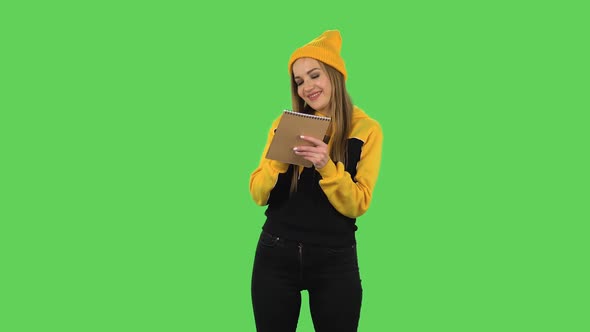 Modern Girl in Yellow Hat Is Standing and Thinking, Then Happy Writing with Pencil in Notebook