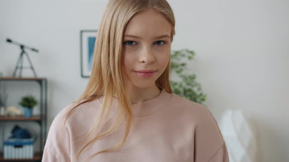 Portrait of Friendly Teenager Waving Hand and Smiling Standing in Apartment Alone